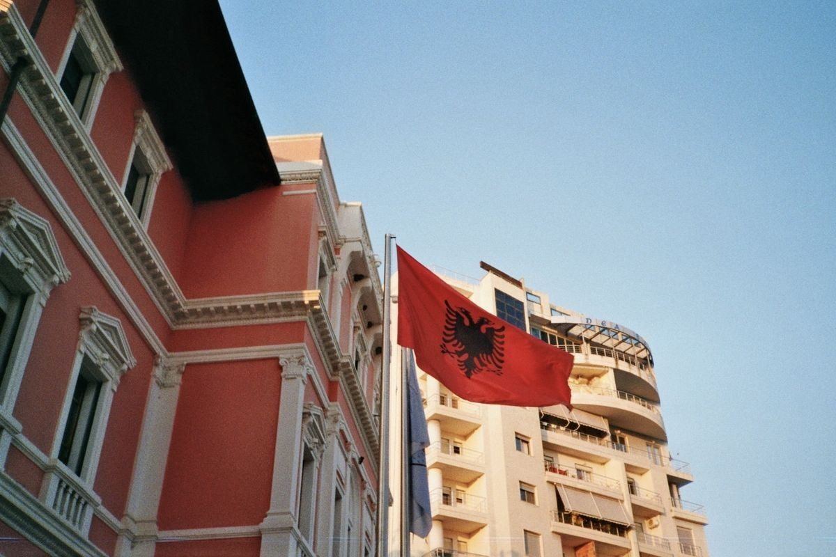 Albanian flag between historic and modern buildings in Tirana