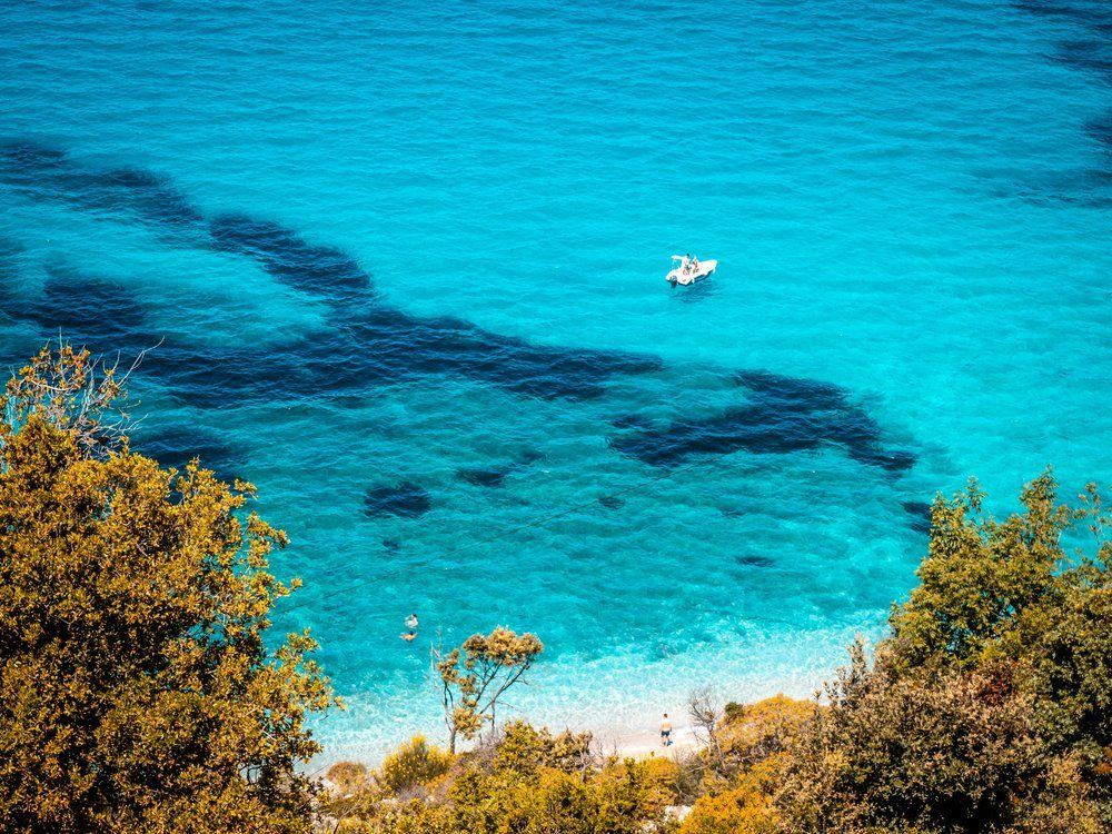 Turquoise sea with a small boat, framed by trees