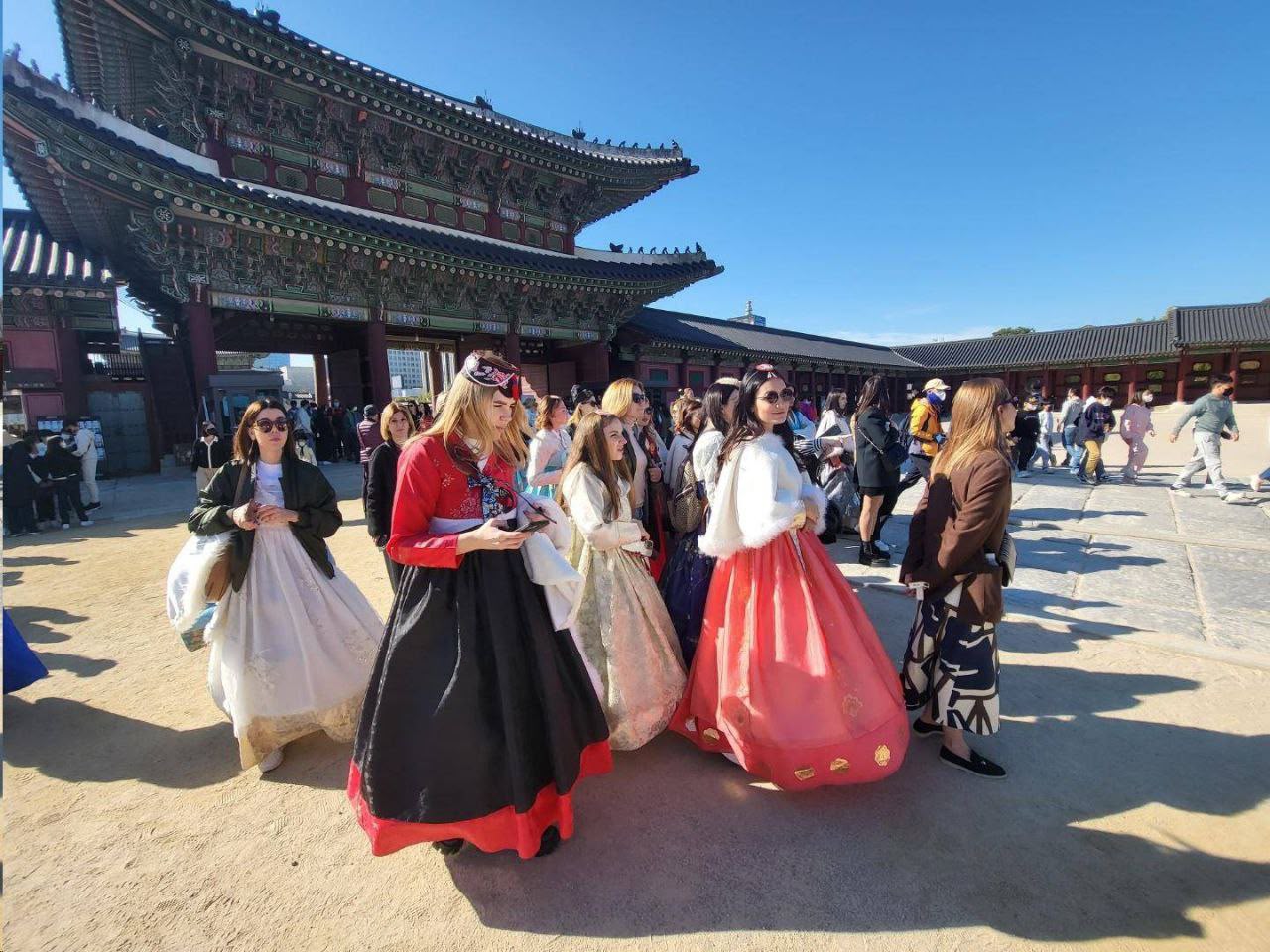 A group in traditional Korean clothing at a historic palace courtyard
